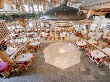 Ein gemütliches Restaurant mit stilvoller Holzverkleidung und angrenzenden Essbereichen. Die Tische sind liebevoll gedeckt und das Lichtkonzept schafft eine einladende Atmosphäre.