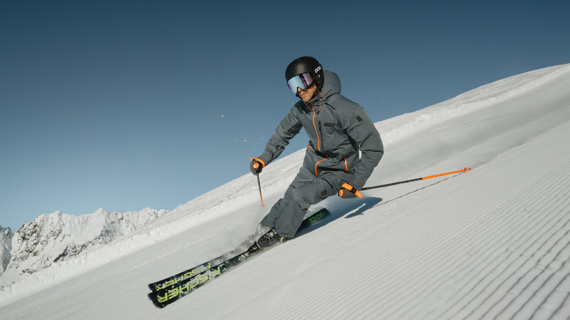 A skier is going down the snow-covered slope. In the background, majestic mountains are visible.