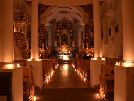 Eine wunderschöne Kirche mit sanfter Beleuchtung und einer beeindruckenden Altaranordnung. Der Raum strahlt eine ruhige und besinnliche Atmosphäre aus.