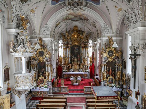 A magnificent church with richly decorated walls and an ornate altar. The interior is flooded with light and exudes a spiritual atmosphere.