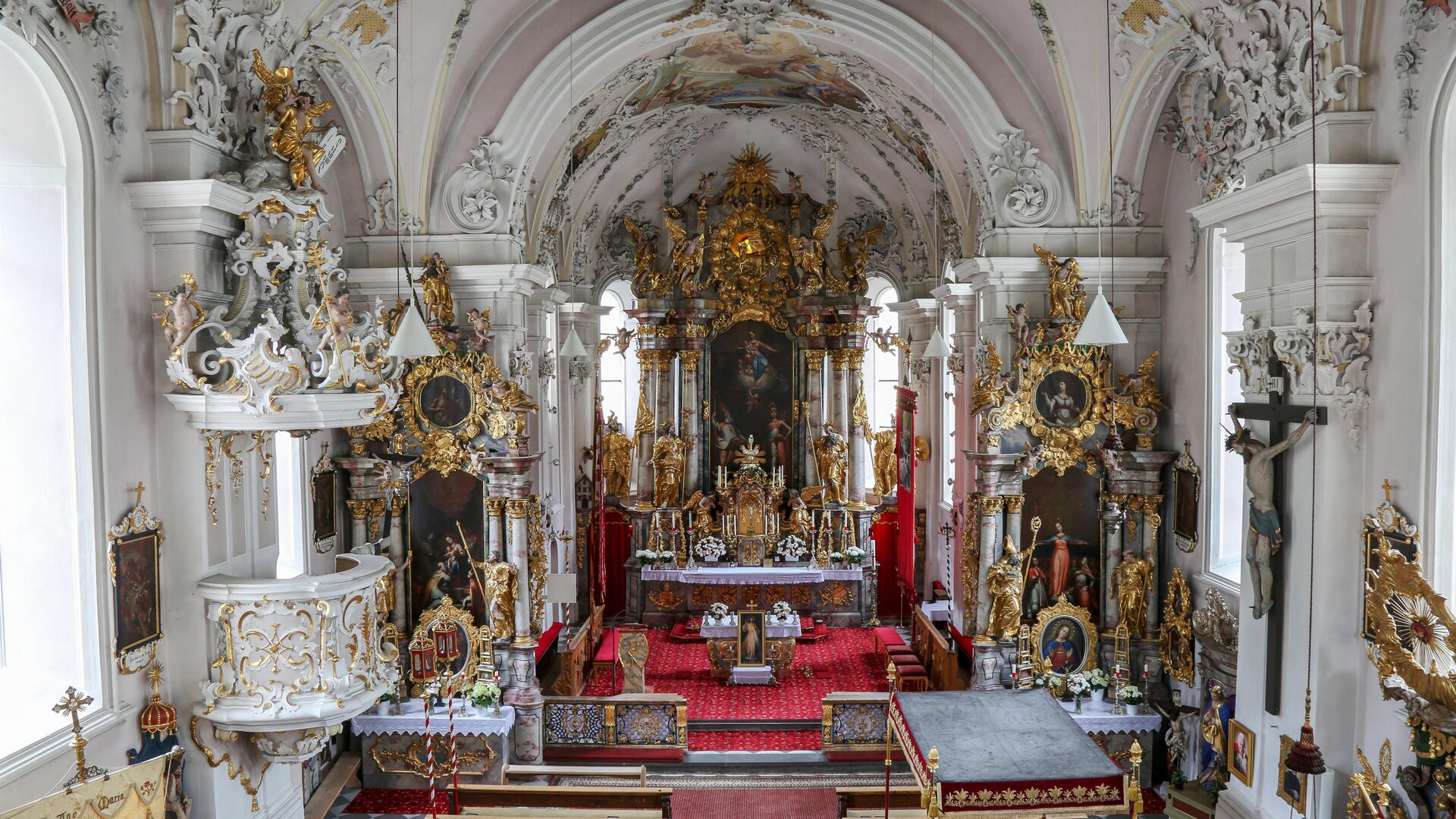 A magnificent church with richly decorated walls and an ornate altar. The interior is flooded with light and exudes a spiritual atmosphere.