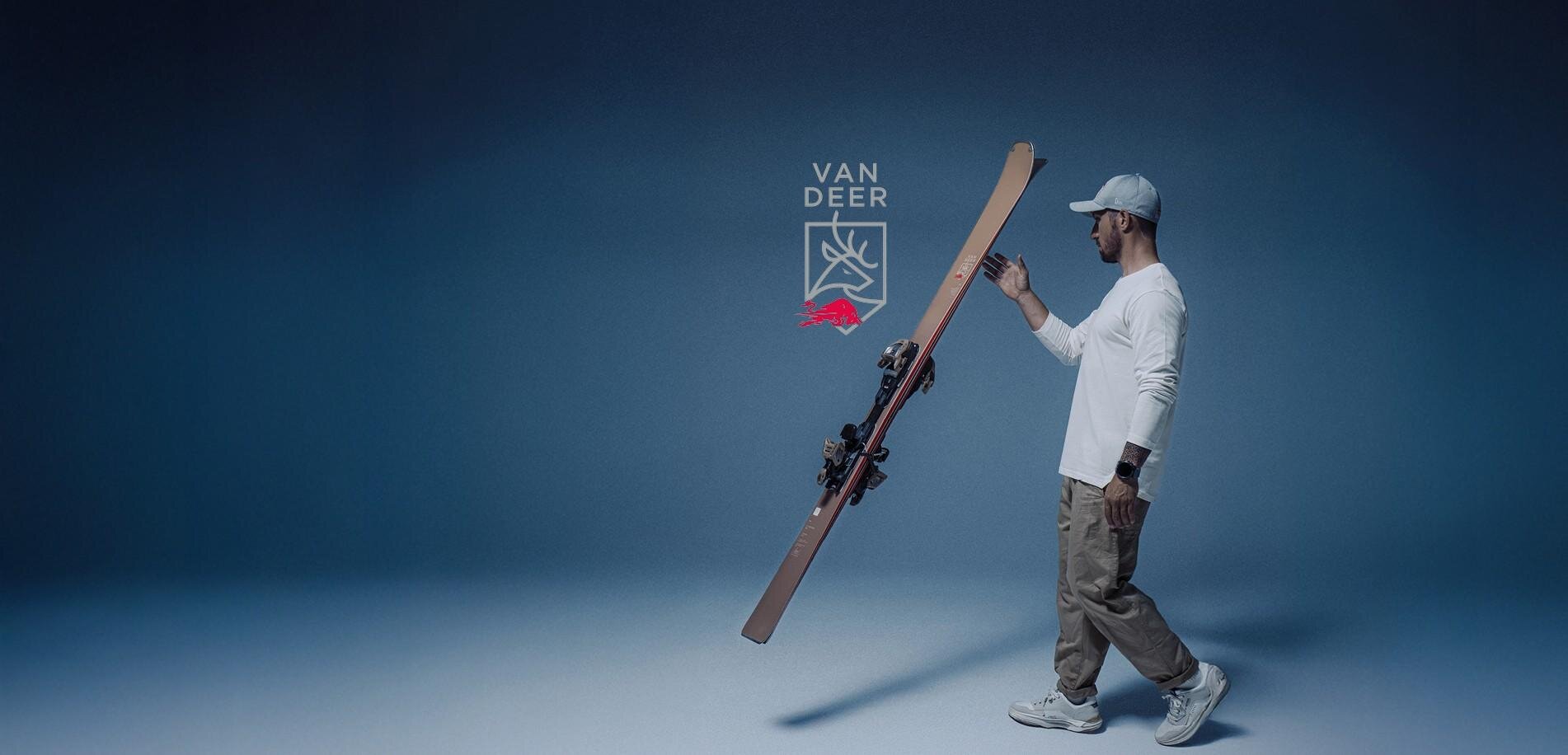 A man is holding skis in a calm, blue environment. In the background, there is a sign for a pop-up testing center in Ischgl from December 5 to 8, 2025.