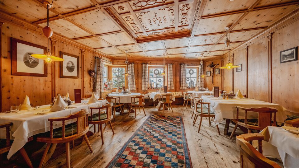 A cozy restaurant with wooden walls and tables. The room is warmly lit and has an inviting ambiance.