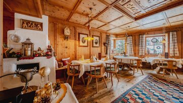 A cozy, wood-paneled restaurant with several table settings. Soft lighting and traditional decor create an inviting atmosphere.