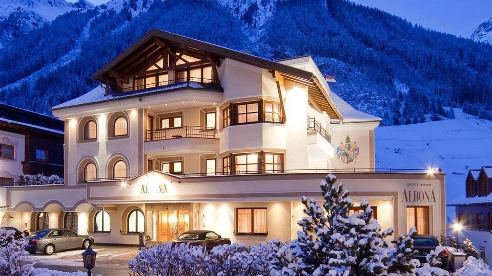 A charming hotel in the mountains, surrounded by snow. The facade of the building radiates coziness and the atmosphere is inviting.