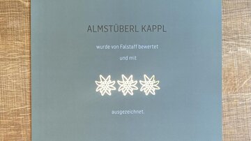 Ein Zertifikat für das Almstüberl Kappl aus dem Falstaff Hüttenguide 2022. Es zeigt, dass das Restaurant bewertet und ausgezeichnet wurde.