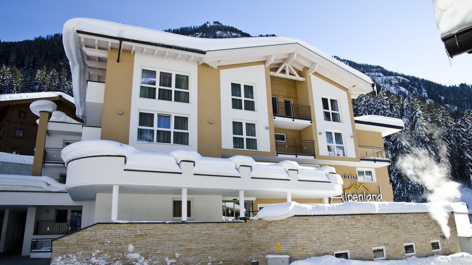 A modern building in a snow-covered landscape. The facade is bright and inviting, surrounded by mountains.