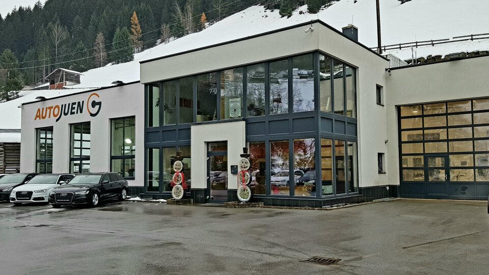 Ein modernes Autohaus mit großen Fenstern und einer hellen Fassade. Umgeben von einer schneebedeckten Landschaft.