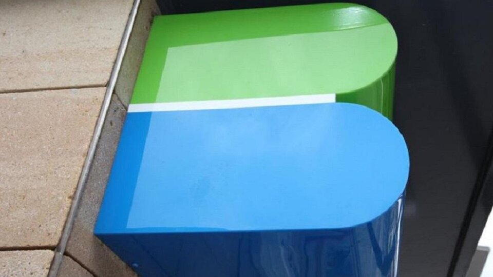 Eine auffällige Gebäudewand mit einem großen, farbigen Logo in Grün und Blau. Das Design ist modern und schlicht.