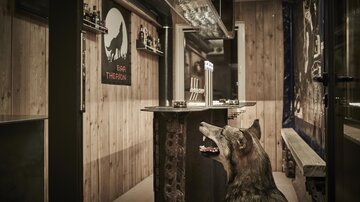 Ein einladender Barbereich mit Holzwänden und einer Theke. Ein Wolfskopf-Dekor und gemütliche Atmosphäre schaffen ein einzigartiges Ambiente.