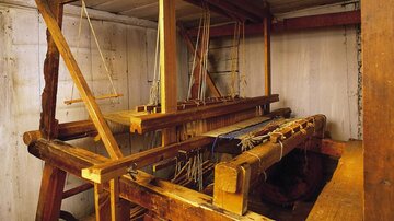 Ein traditioneller Webstuhl aus Holz in einem Innenraum. Die Struktur zeigt verschiedene Teile für die Webtechnik.