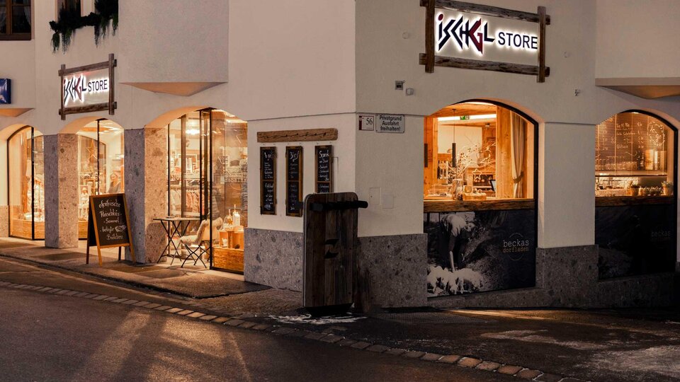 A store named "ISCHGL STORE" on a quiet street.  
The windows are illuminated and display various products.