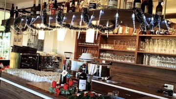Eine moderne Bar mit Holzregalen und einer eleganten Theke. Die Flaschen sind ordentlich angeordnet und es gibt gläserne Lichtakzente.