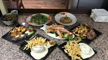 Ein festliches Essen auf einem Tisch mit verschiedenen Gerichten. Es gibt Pommes, gebratenes Hähnchen, Salat und Saucen.