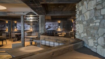 Ein gemütliches Restaurant mit Holzelementen und Steinwänden. Die Beleuchtung schafft eine warme und einladende Atmosphäre.