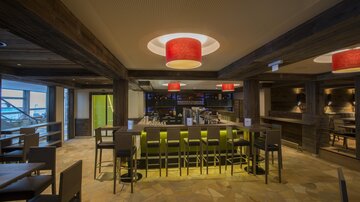 Ein modernes Restaurant mit einer stilvollen Bar. Rote Lampen hängen von der Decke und schaffen eine einladende Atmosphäre.