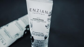 Eine Handcreme in einer eleganten Tube mit dem Aufdruck "ENZIAN". Die Verpackung zeigt florale Motive und hebt die pflegenden Eigenschaften hervor.