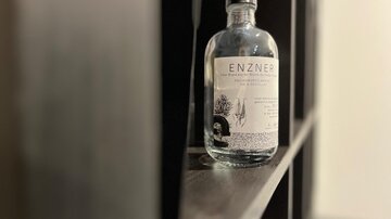 Eine Flasche ENZNER auf einem Regal. Die Flasche ist klar und hat ein schlichtes, elegantes Design.