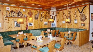 A cozy restaurant with wooden walls and a rustic decor. Various trophies and souvenirs hang on the walls.