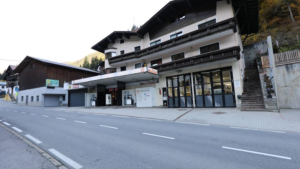 Eine ruhige Straße mit einem großen, traditionellen Gebäude. Das Gebäude scheint Geschäfte und Dienstleistungen anzubieten.