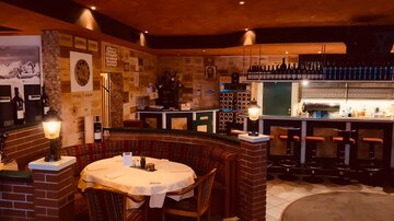 Ein gemütliches Restaurant mit Holzdekor und einer einladenden Bar. Die Atmosphäre ist warm und einladend, ideal für ein Abendessen.