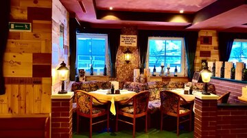 Gemütliches Restaurant mit Holzwänden und bequemen Sitzplätzen. Große Fenster sorgen für viel Licht und einen einladenden Blick nach draußen.