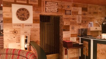 Ein gemütlicher Restaurantbereich mit einer Wand aus Holzpanelen und einer großen Wanduhr. Die Einrichtung ist rustikal und einladend.