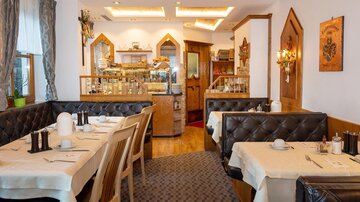 Ein gemütliches Restaurant mit eleganten Tischen und stilvollem Interieur. Die Atmosphäre ist einladend und warm gestaltet.