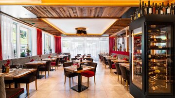 A modern restaurant with elegant décor and warm wooden accents. The tables are beautifully set and invite guests to linger.