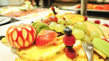 Ein bunter Obstteller mit verschiedenen Früchten, darunter Äpfel, Trauben, Ananas und Beeren. Schön dekoriert, bietet er eine Vielzahl an Aromen und Farben.