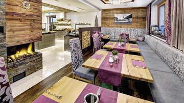 Ein gemütliches Restaurant mit Holzdekor und eleganten Tischen. Die warme Atmosphäre wird durch einen Kamin und stilvolle Einrichtung unterstrichen.