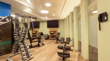 Ein modernes Fitnessstudio mit verschiedenen Geräten zum Training. Es gibt eine freundliche Atmosphäre und viel Platz zum Trainieren.