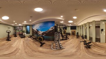 Ein modernes Fitnessstudio mit verschiedenen Trainingsgeräten und einer inspirierenden Berglandschaft an der Wand. Der Raum ist hell und einladend, ideal für das Workout.