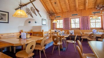 A cozy restaurant with wooden furniture and a rustic ambiance. The interior features large windows and decorative elements that create an inviting atmosphere.