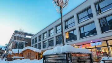 A modern building in the snow with large windows. The surroundings are wintry and slightly decorated.