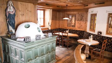 Ein gemütliches Restaurant mit Holzverkleidung und traditionellen Möbeln. Eine Statue in der Ecke verleiht dem Raum eine rustikale Atmosphäre.