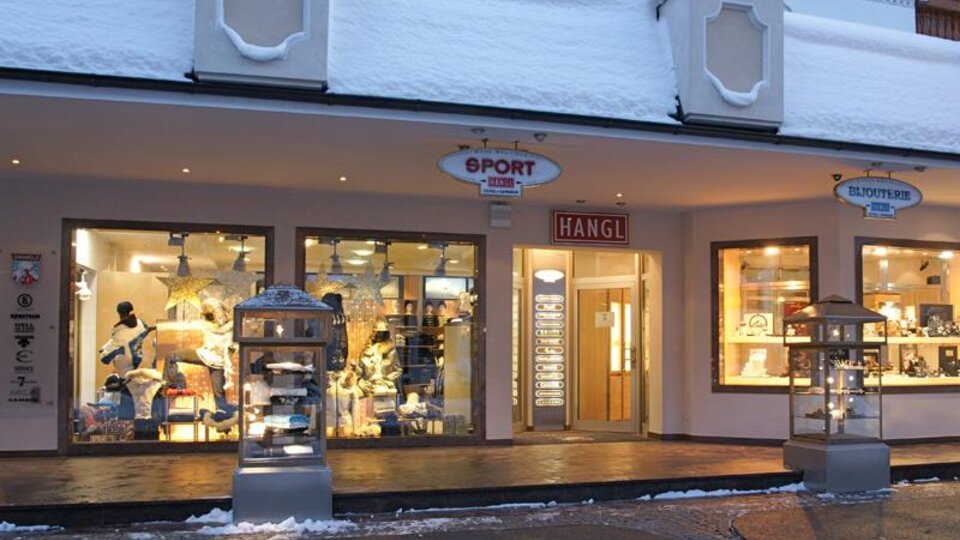 A sports store with a snow-covered facade. In the shop window, various sports items and clothing are visible.