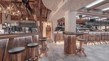 Ein modernes Restaurant mit Holzdekor und stilvollen Barhockern. Die angenehme Beleuchtung schafft eine einladende Atmosphäre.