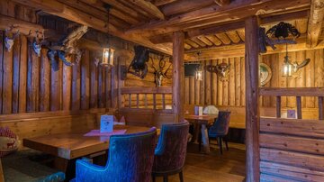Ein rustikales Restaurant mit Holzwänden und gemütlichen Sitzbereichen. Die Atmosphäre ist warm und einladend.