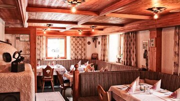 Ein gemütliches Restaurant mit Holzmöbeln und weißen Tischdecken. Die Atmosphäre ist einladend mit sanftem Licht und einem rustikalen Charme.