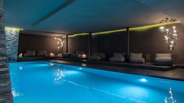 An elegant wellness area with a illuminated pool and comfortable loungers. Soft lighting creates a relaxing atmosphere.