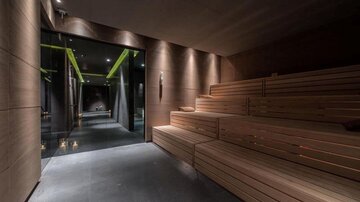 A modern wellness environment with a wooden sauna and dimmed lighting. The room conveys a relaxing atmosphere.