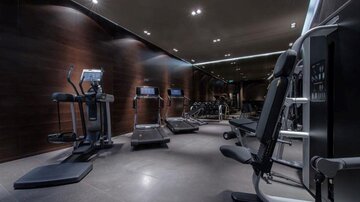 A modern gym with various fitness equipment. The room has an elegant atmosphere with dim lighting.