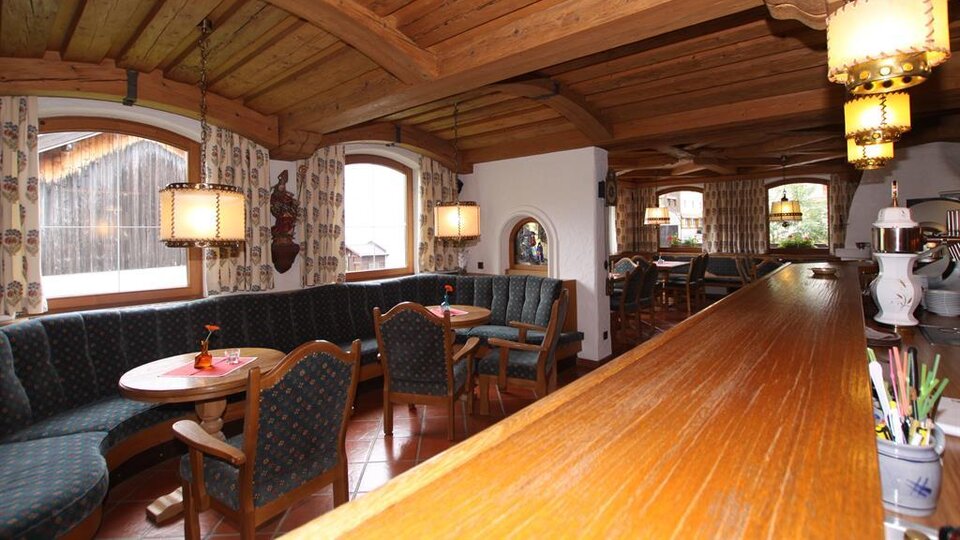 Ein gemütliches Restaurant mit Holzmöbeln und einer einladenden Atmosphäre. Die Fenster bieten einen Blick auf die Umgebung und die angenehme Beleuchtung sorgt für eine warme Stimmung.