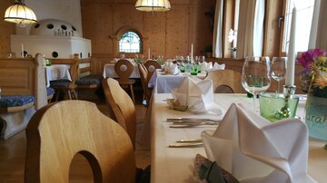 Ein gemütliches Restaurant mit Holzmöbeln und schön gedeckten Tischen. Die Fenster lassen viel Tageslicht hinein und es herrscht eine einladende Atmosphäre.