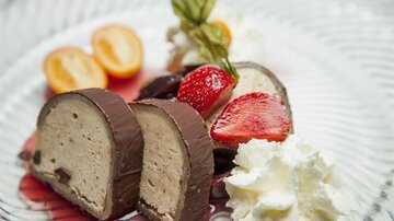 Eine köstliche Dessertplatte mit schokoladigem Schokoladeneis, Erdbeeren und Kiwis. Creme und frische Minze runden das Arrangement ab.