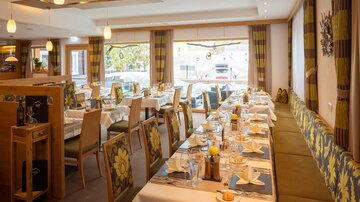 An elegant restaurant with festively set tables. Bright colors and large windows create an inviting atmosphere.