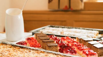 A selection of delicious cakes and pastries on a table. In the background, there is a small pot.