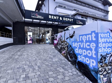 Ein moderner Geschäftseingang mit dem Schriftzug "RENT & DEPOT". Die Fassade ist bunt gestaltet und lädt zur Entdeckung ein.
