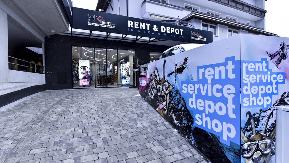 Ein moderner Geschäftseingang mit dem Schriftzug "RENT & DEPOT". Die Fassade ist bunt gestaltet und lädt zur Entdeckung ein.